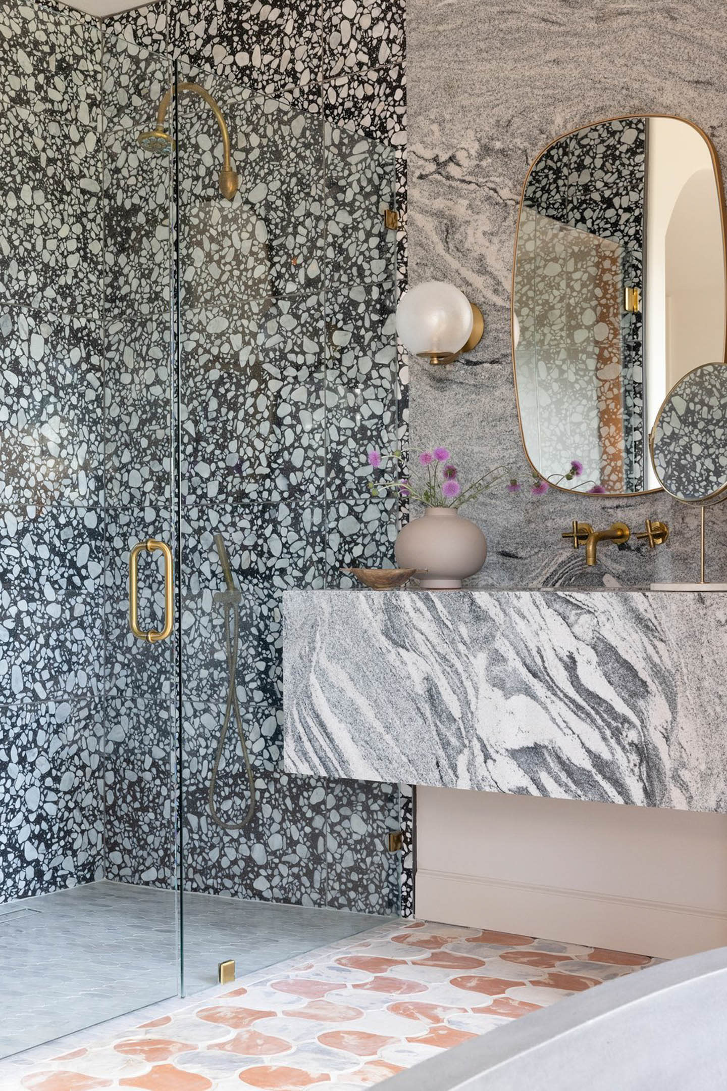 bathroom with grey veined marble vanity and a black and white stone-tiled shower