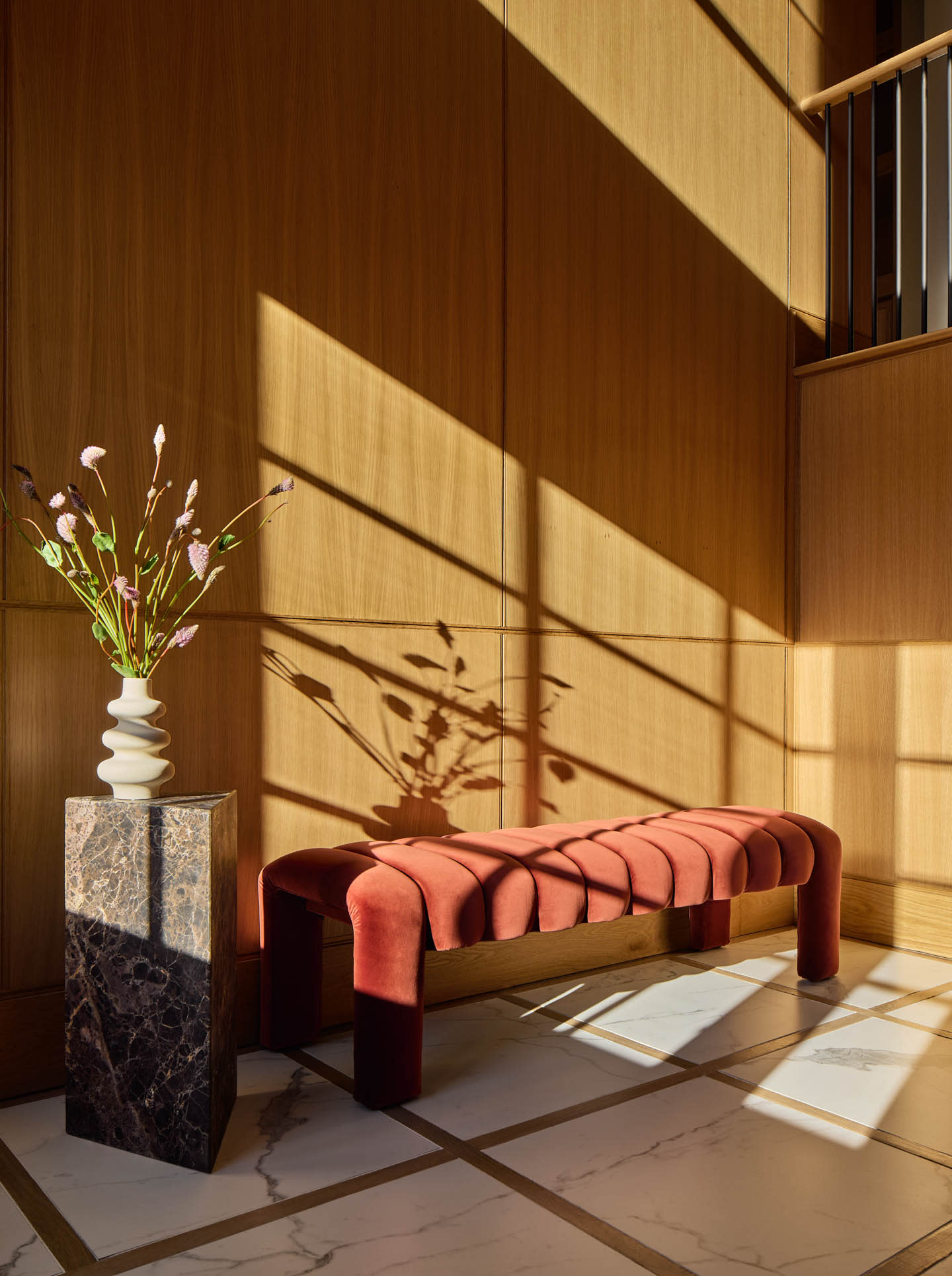 contemporary home landing with a wood wall, stone table and a red bench