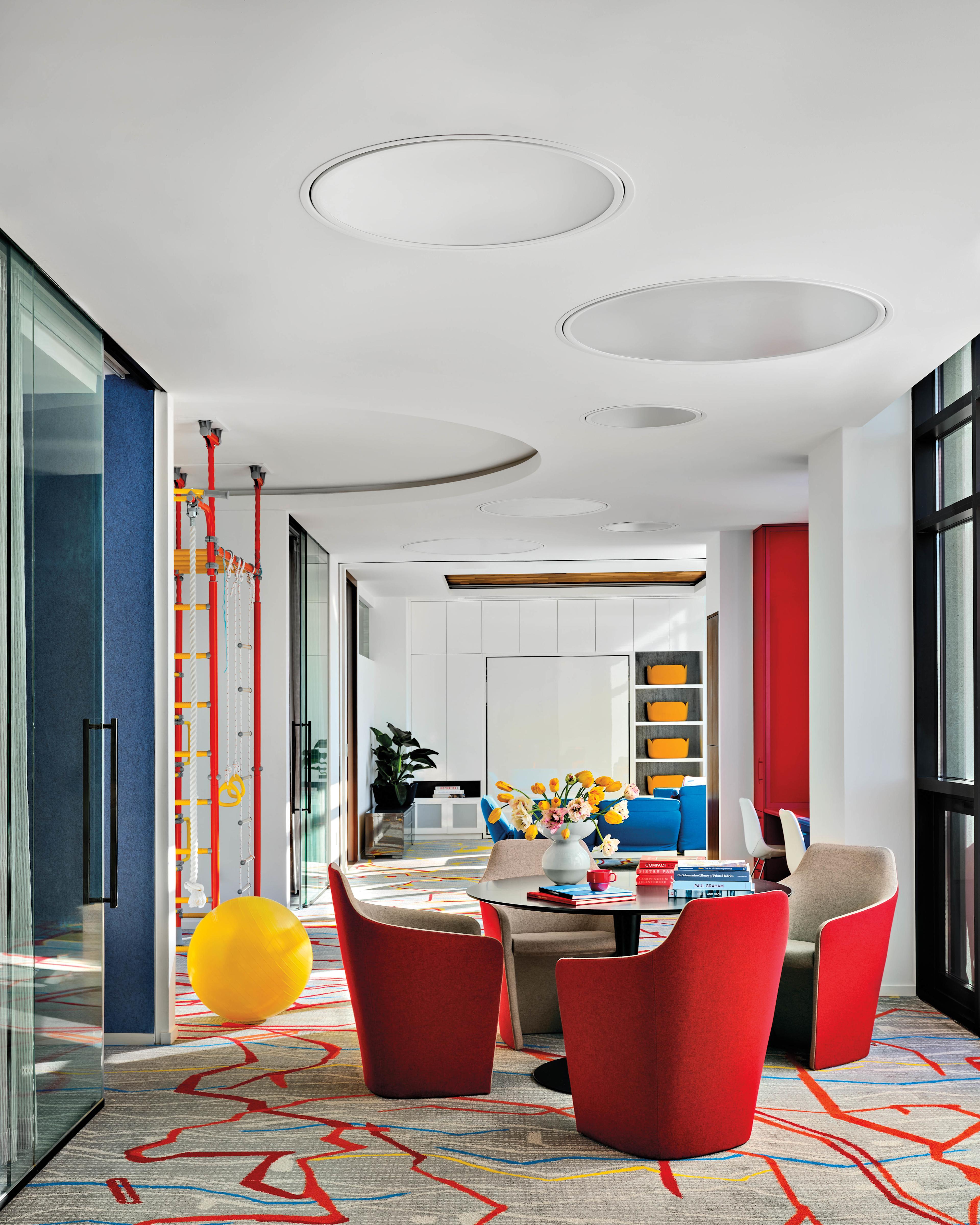 living area with bright red chairs atop a graphic grey and red carpet