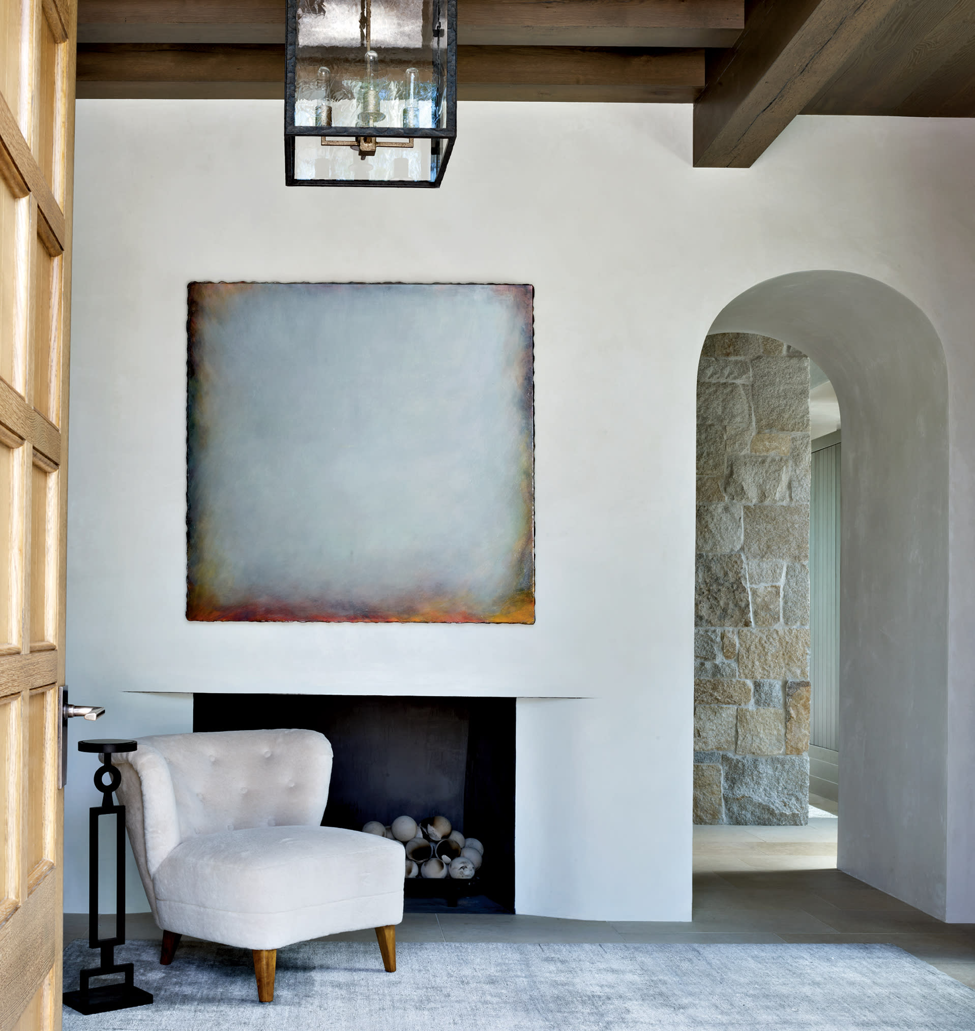entry hall of a neutral Colorado home featuring an arched doorway and exposed beam ceiling