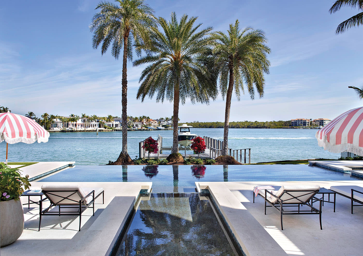 infinity pool flanked by midcentury pink and white striped umbrellas 