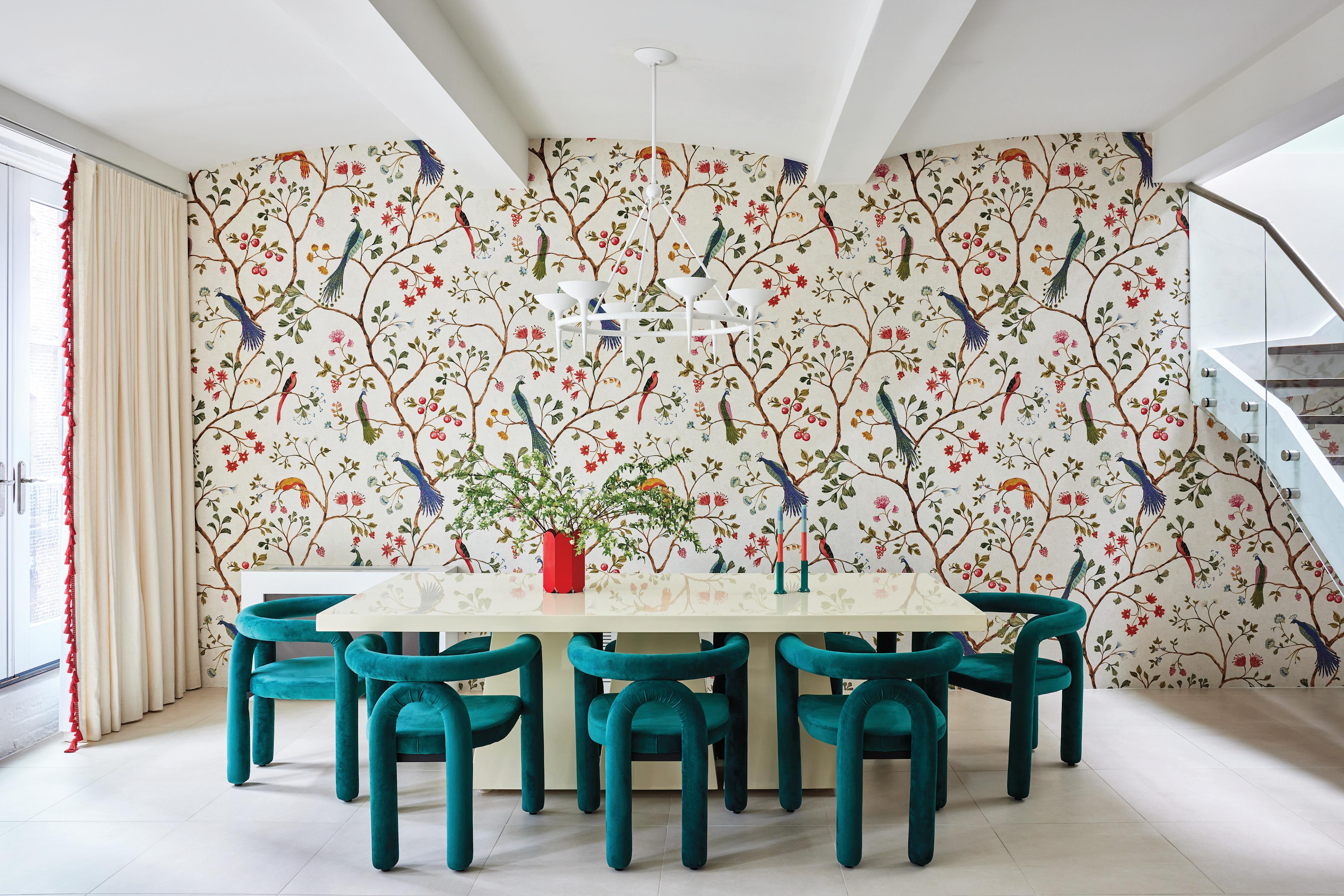 dining room with bird-motif wallpaper and modern teal dining chairs around a lacquered CB2 table