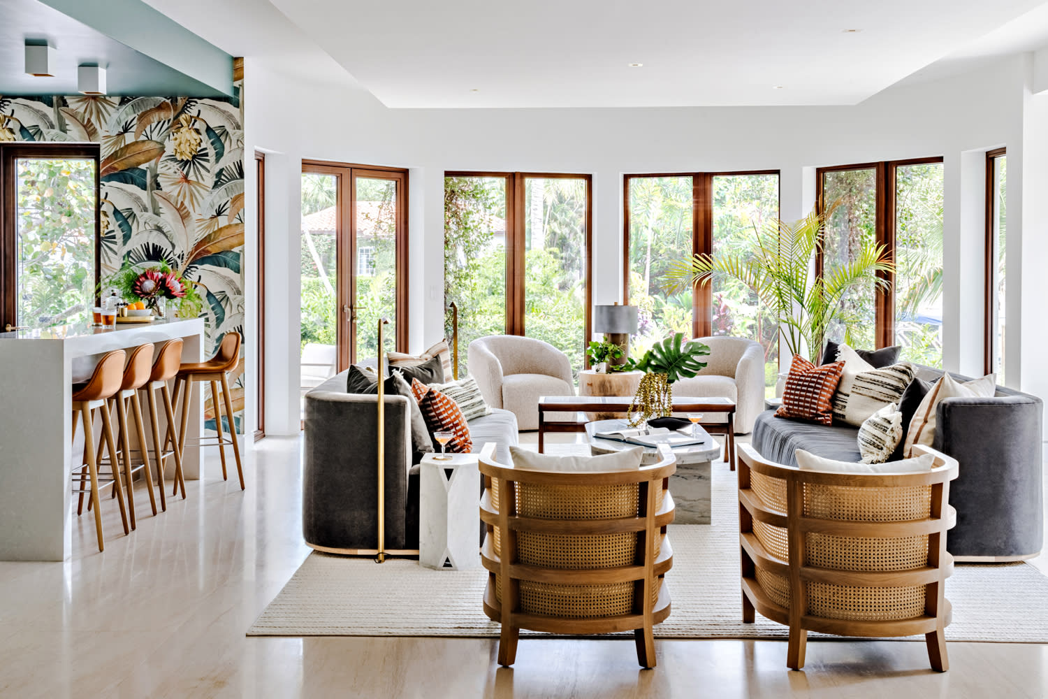 modern living room with an adjacent bar covered in tropical wallpaper and a teal ceiling